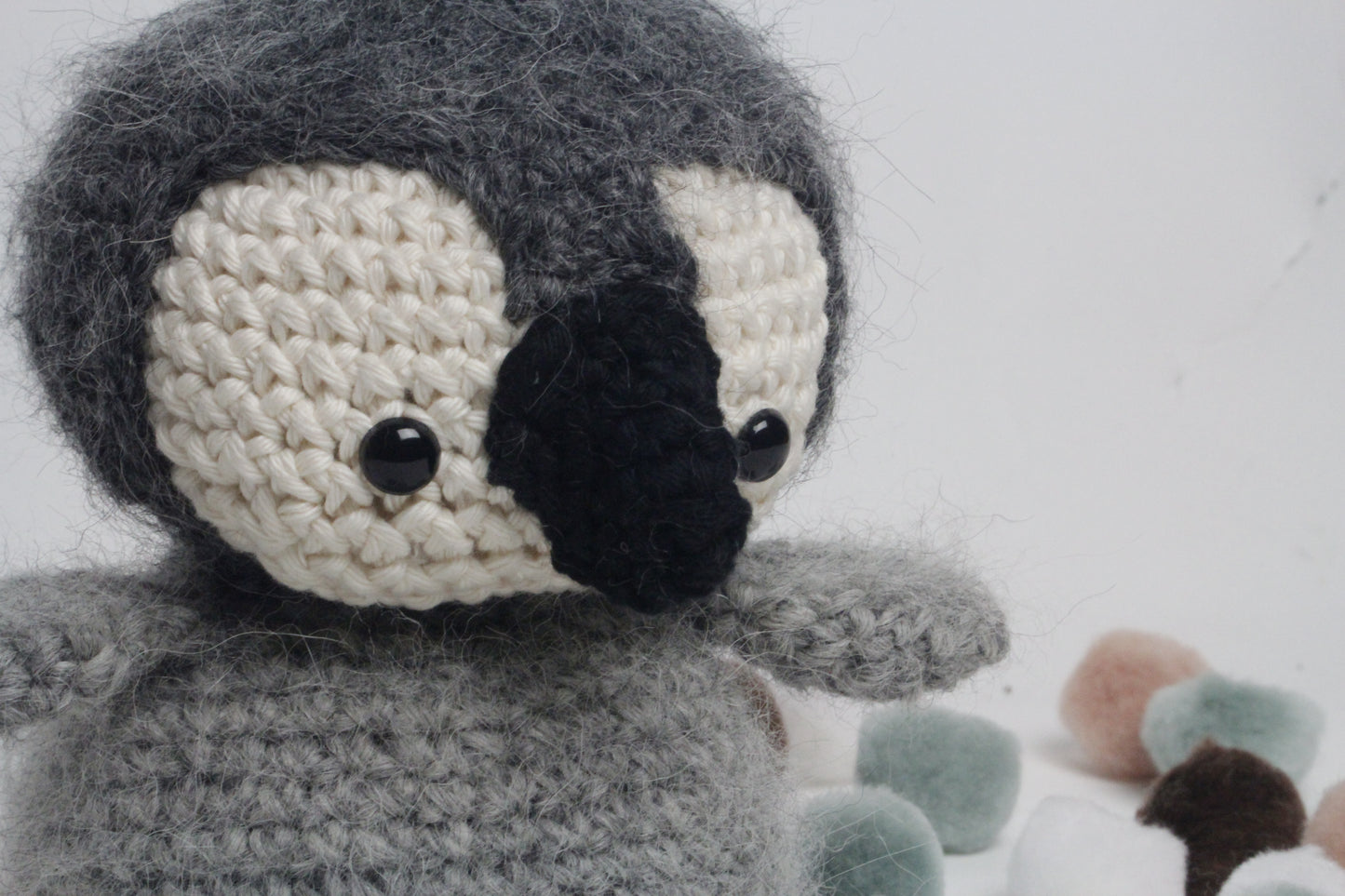 Crocheted penguin toy with a black beak on a white background