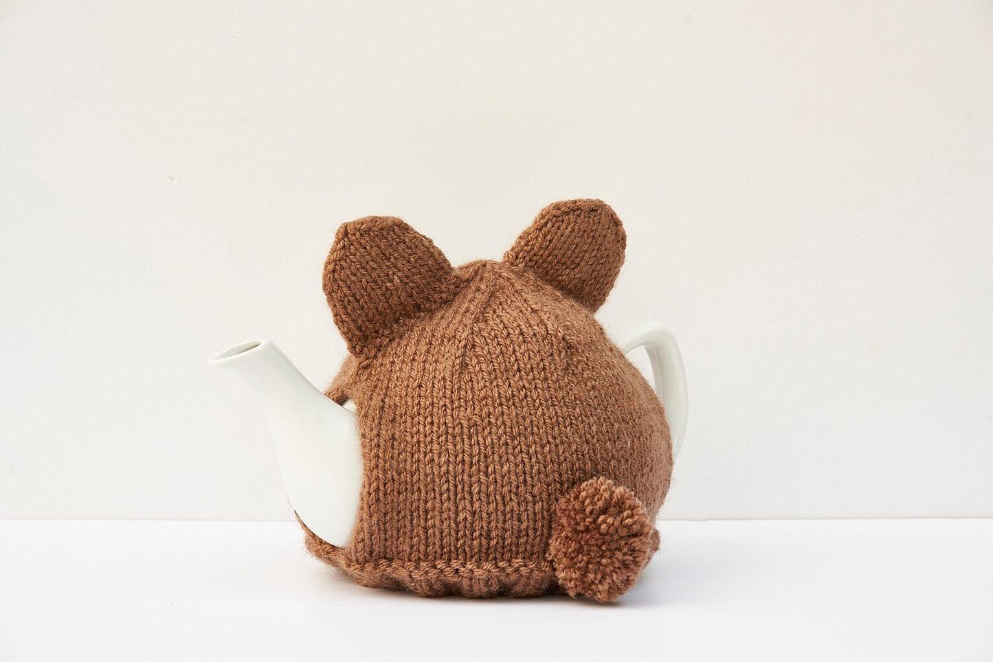 Knitted brown bear tea cosy with pom pom tail. Washable fits 1 litre teapot.