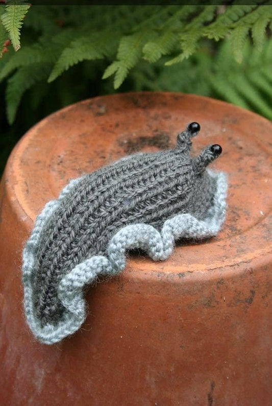 Hand knitted slug with frilly skirt and beady eyes.