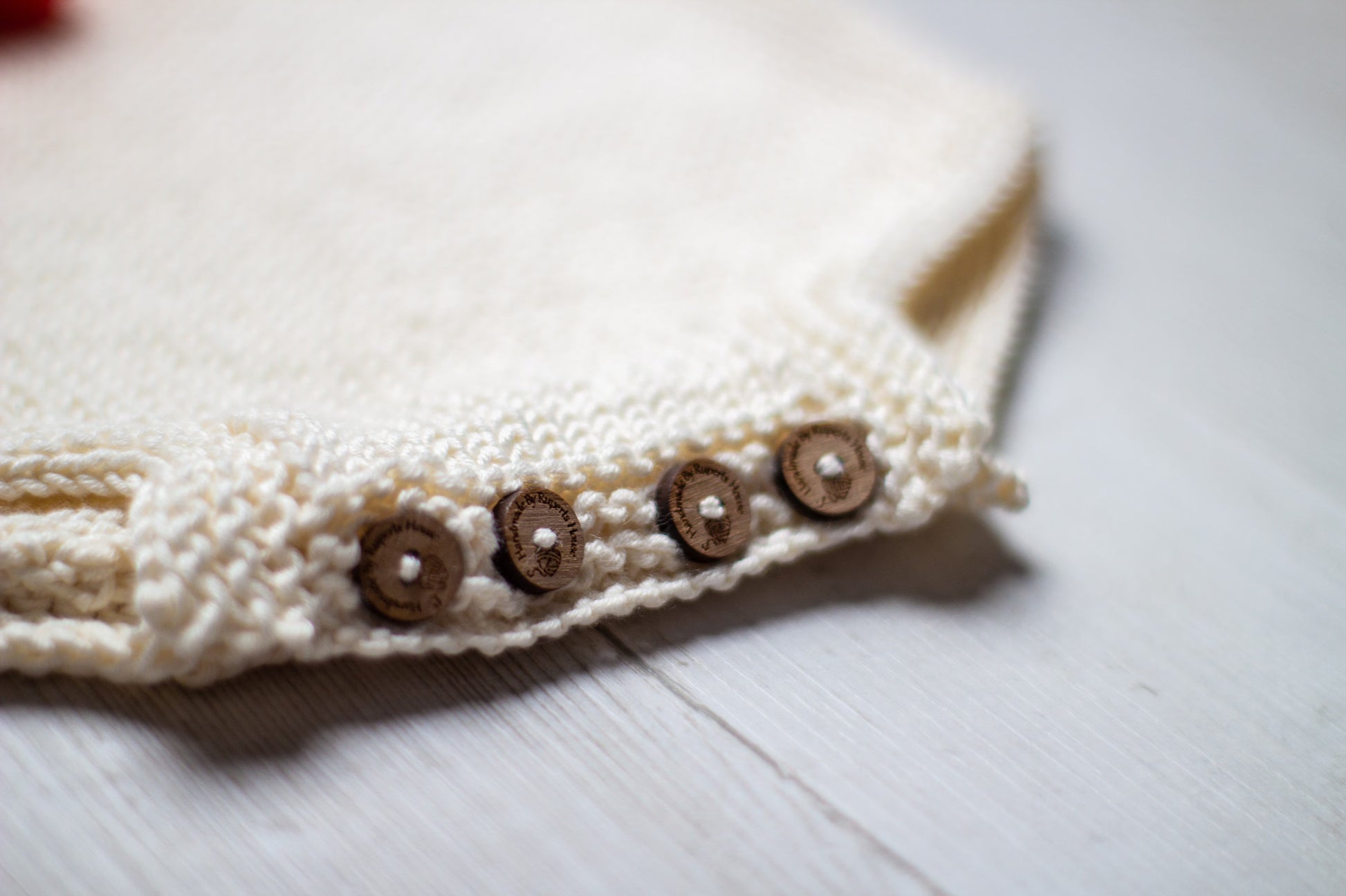 Close-up of baby romper suit wooden button closure.  