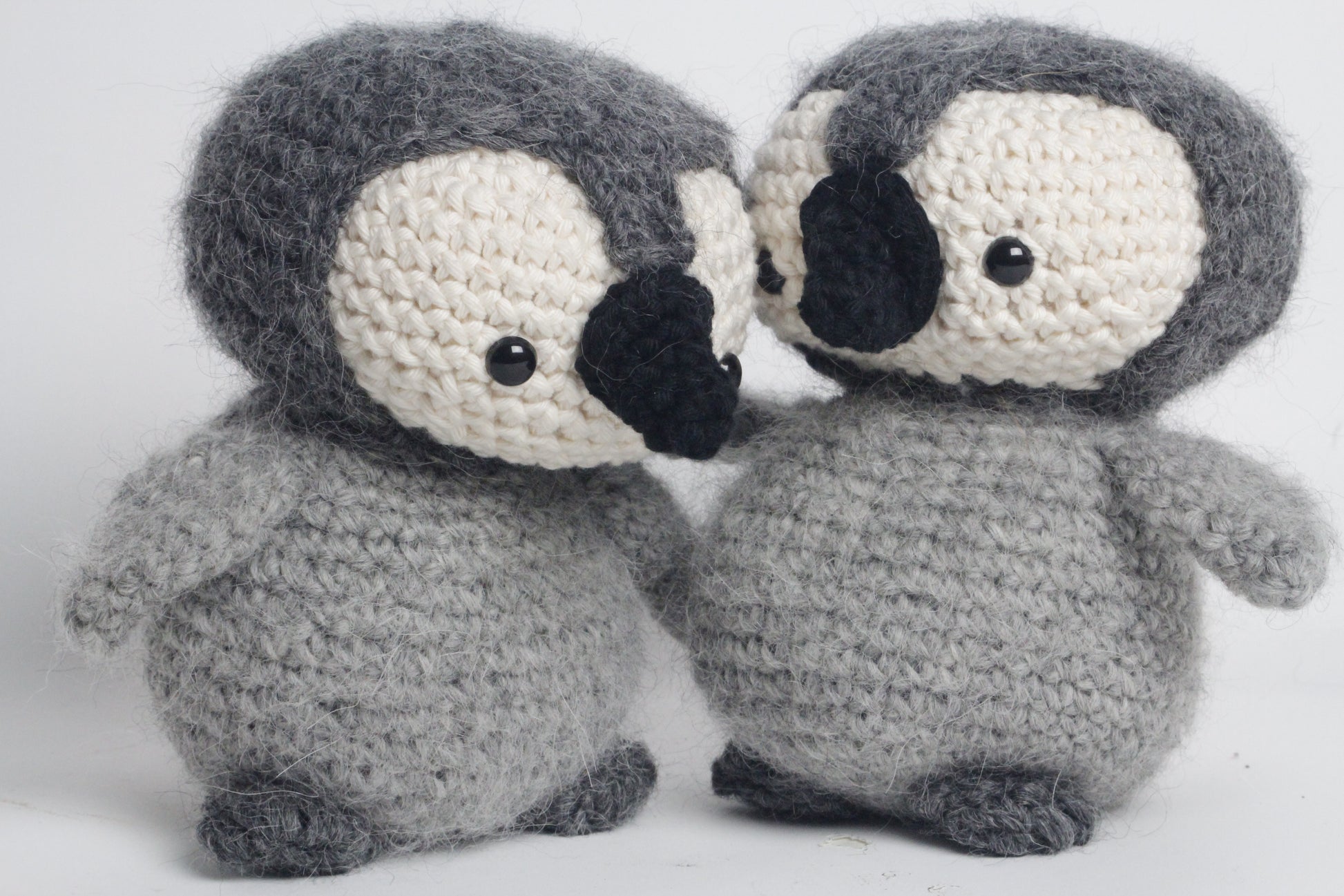 Two crocheted penguin toys on a white background