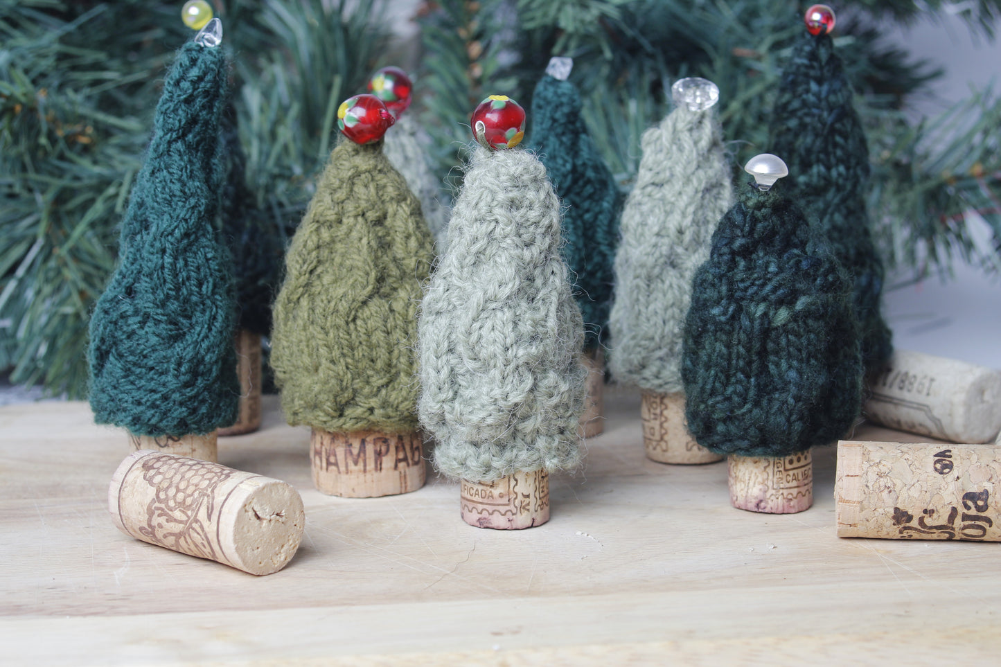 Knitted Christmas trees on corks with a snowy landscape background