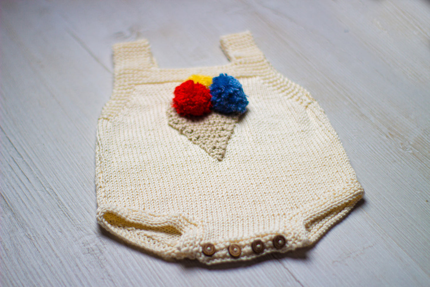 Knitted baby romper with colorful ice cream cone and button flap closure.
