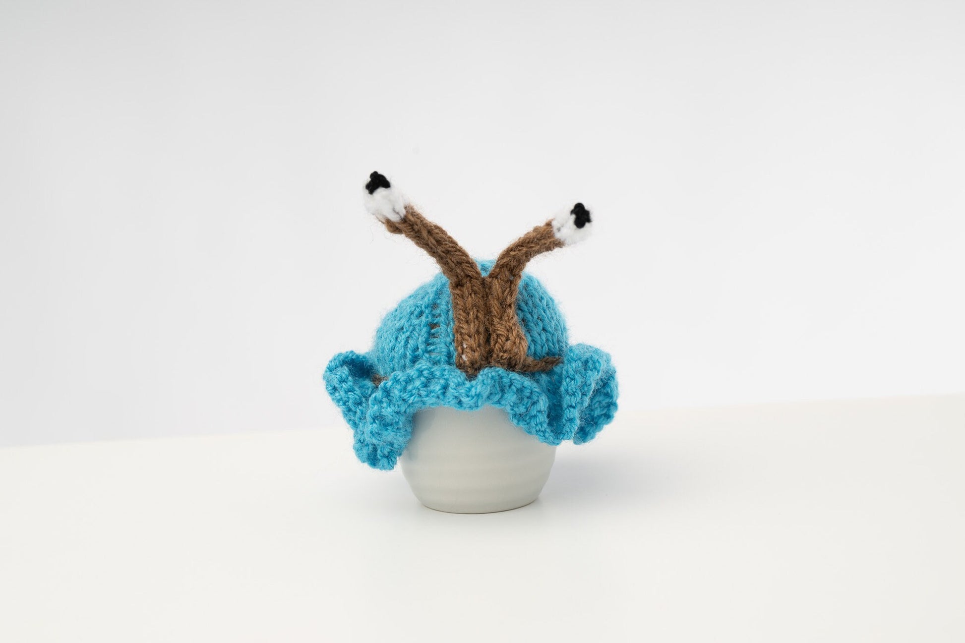 Hand knitted blue snail tea cosy with frilly bottom and boggly eyes.  Fits 6 cup and 2 cup pots.
