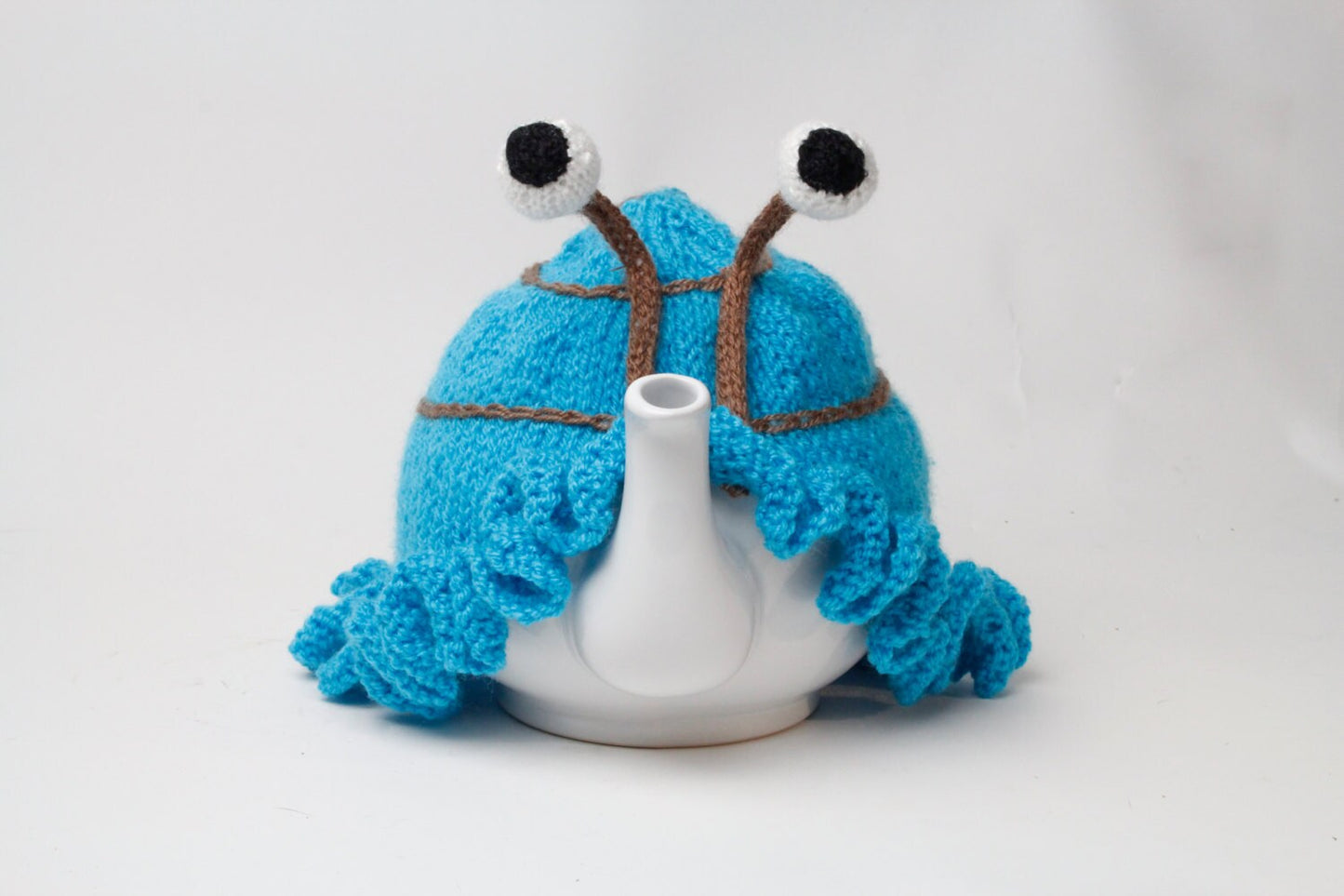 Hand knitted blue snail tea cosy with frilly bottom and boggly eyes.  Fits 6 cup and 2 cup pots.
