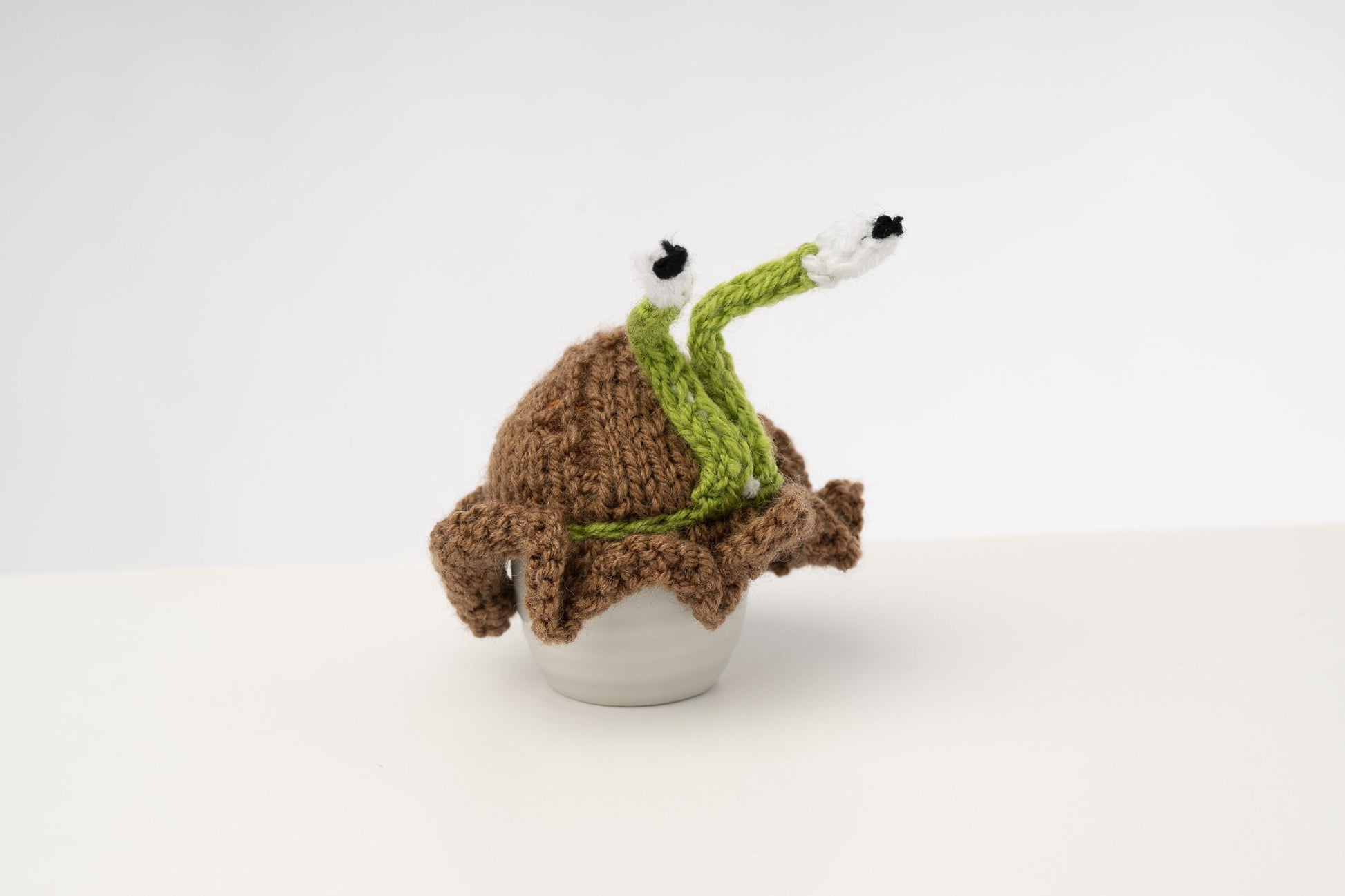 Knitted brown snail tea cosy with frilly bottom. Washable. 2 cup and 6 cup sizes