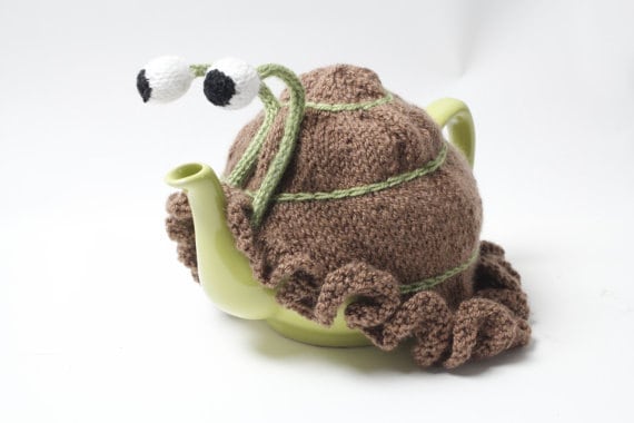 Knitted brown snail tea cosy with frilly bottom. Washable. 2 cup and 6 cup sizes