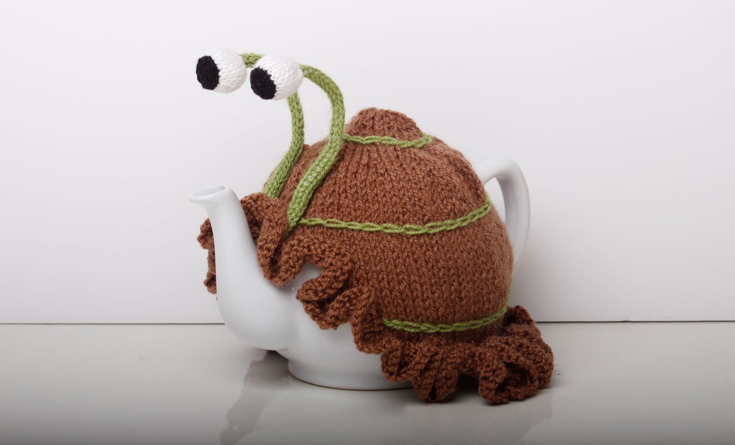 Knitted brown snail tea cosy with frilly bottom. Washable. 2 cup and 6 cup sizes