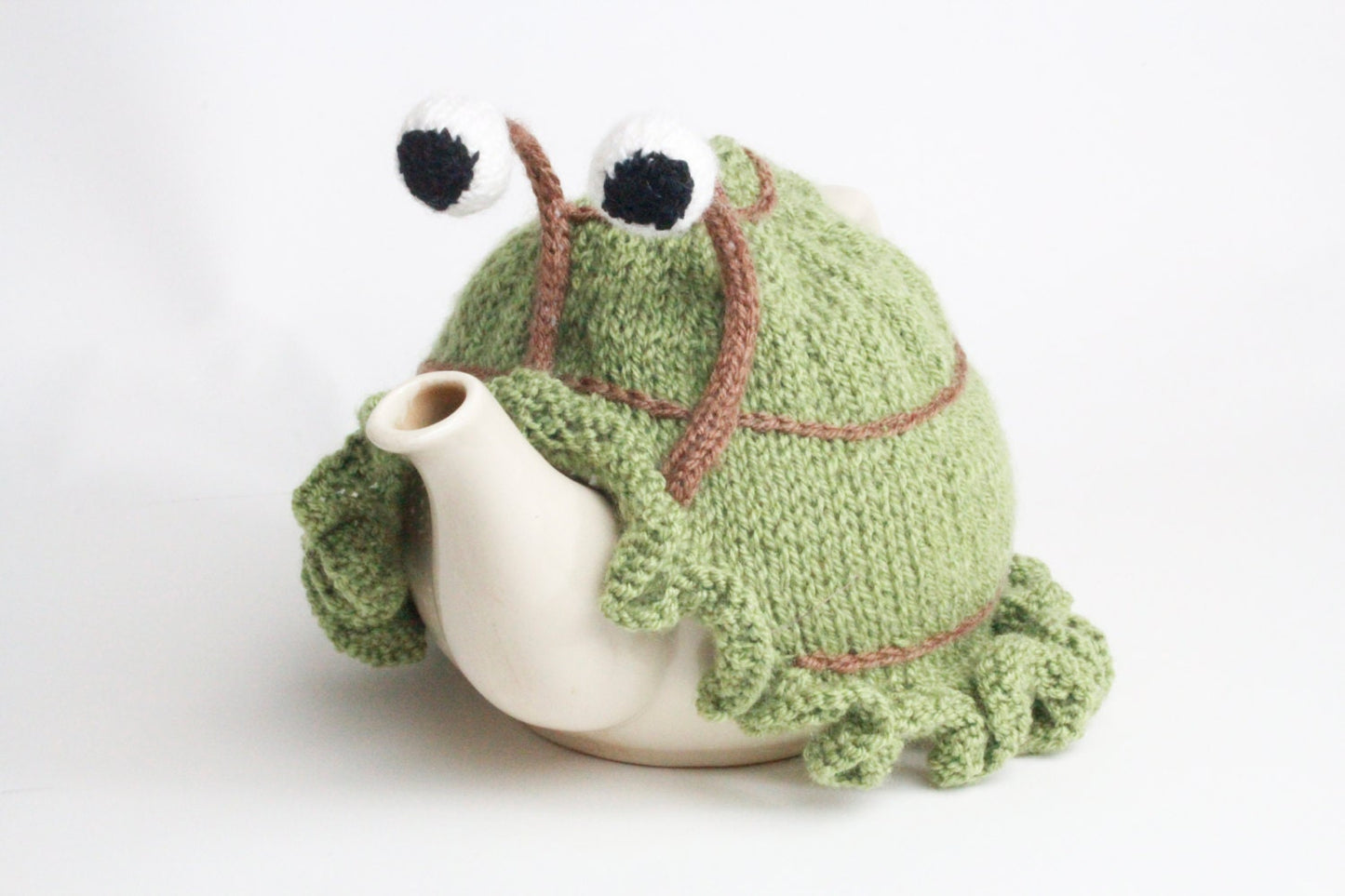 Knitted green snail tea cosy with frilly bottom. Washable fits 6 cup and 2 cup pots.