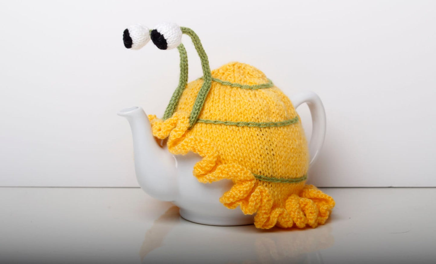 Knitted yellow snail tea cosy with frilly bottom. 6 cup and 2 cup sizes. Washable.